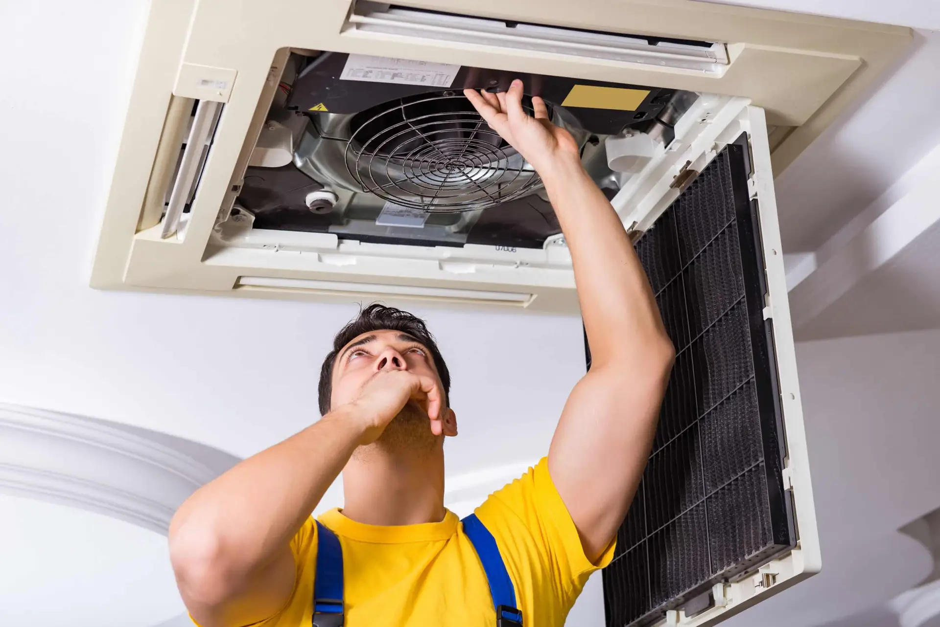 Repairman repairing ceiling air conditioning unit